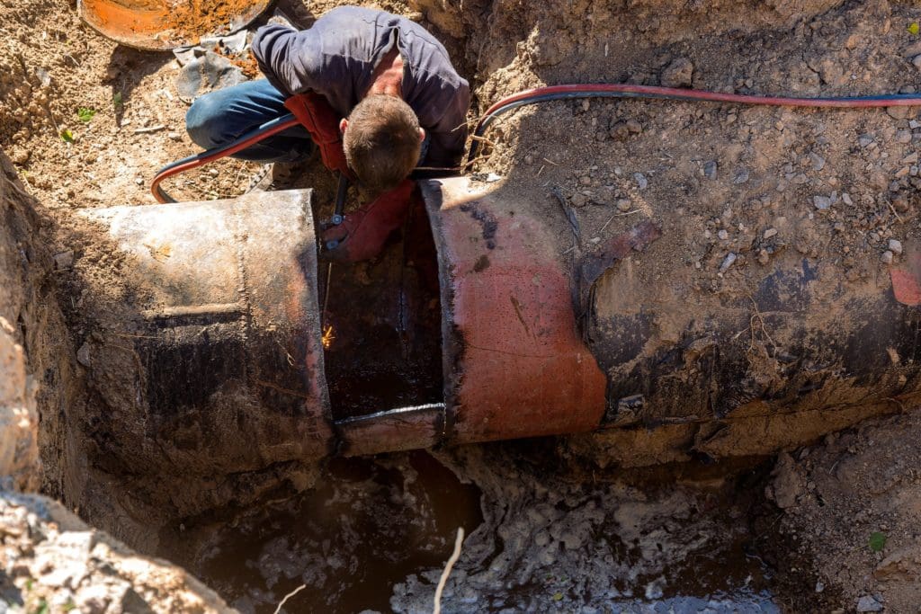 eplacement, dismantling of old worn water pipes. Welding work on cutting old rusty pipes. Replacement of old rusty metal water pipes. Welder cuts metal with gas torch. Internal pipeline corrosion is eating away the pipe surface