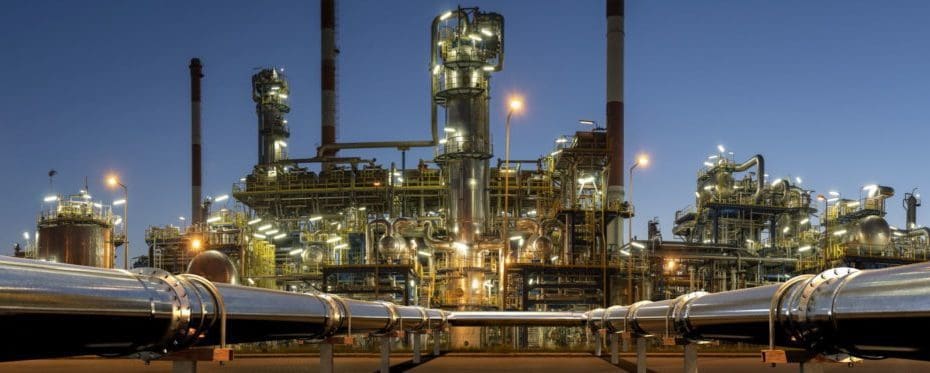 pipelines leading to a refinery structure comprised of piping systems, pressure vessels, slug catchers, etc. set against a dusky sky